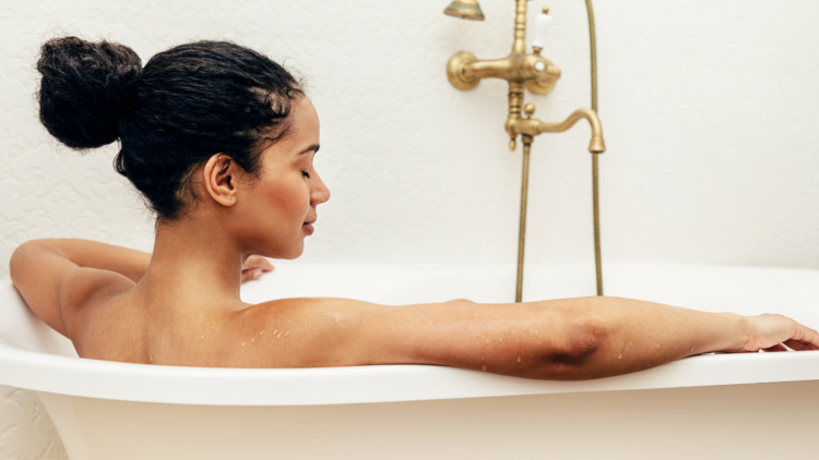 Photo of young relaxed woman soaking in a bath.