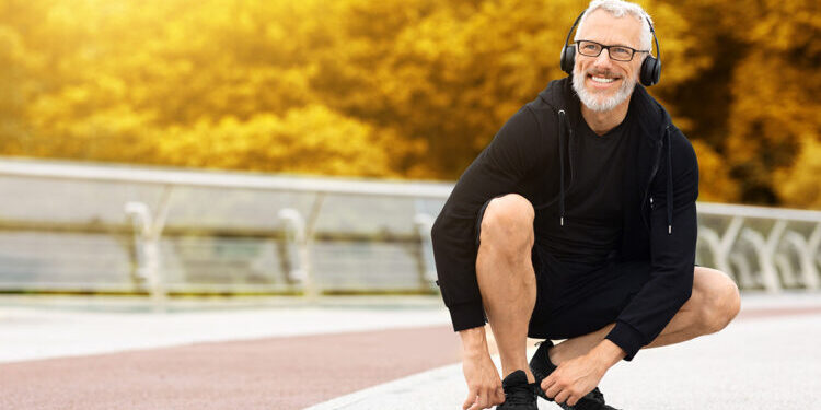 Photo of happy senior outdoors tying shoelace.