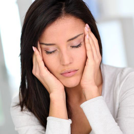 Photo of woman with eyes closed touching her temples