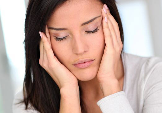 Photo of woman with eyes closed touching her temples